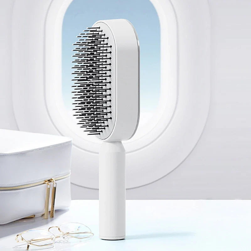 White self-cleaning hair brush with retractable nylon bristles and ergonomic plastic handle, designed for easy hair removal and gentle scalp massage; suitable for all hair types and promotes healthy hair growth.