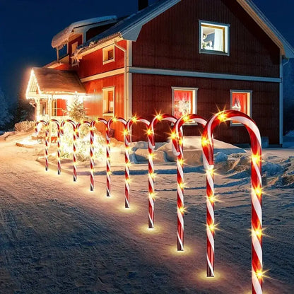 Solar-powered Christmas candy cane lights illuminating a snowy pathway in a festive outdoor setup.