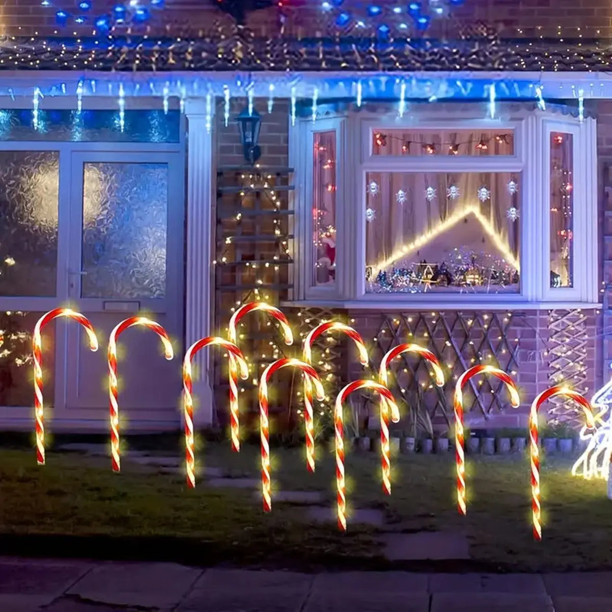 Solar-powered Christmas candy cane lights illuminating a snowy pathway in a festive outdoor setup.